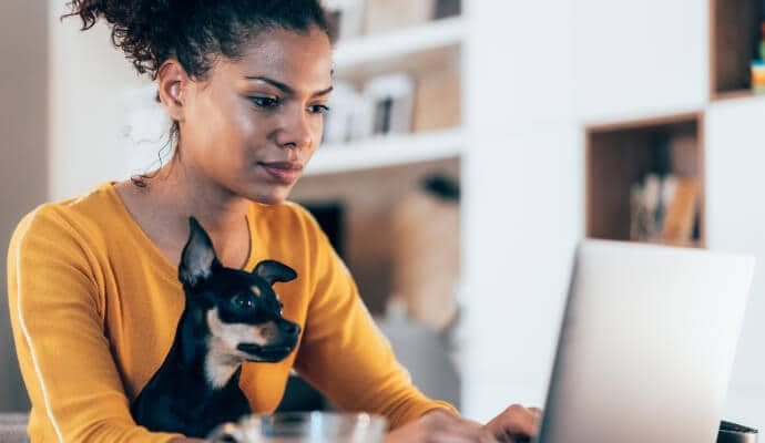 Femme utilisant un ordinateur portable alors que son chien est assis sur ses genoux