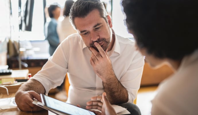 Homme regardant un autre homme utiliser un ordinateur portable