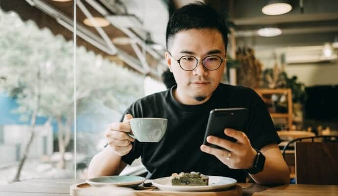 Homme profitant d'un repas en regardant le téléphone portable qui lance Norton 360 Standard.