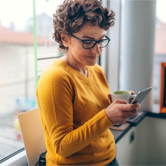 Femme tenant une tasse et un téléphone portable