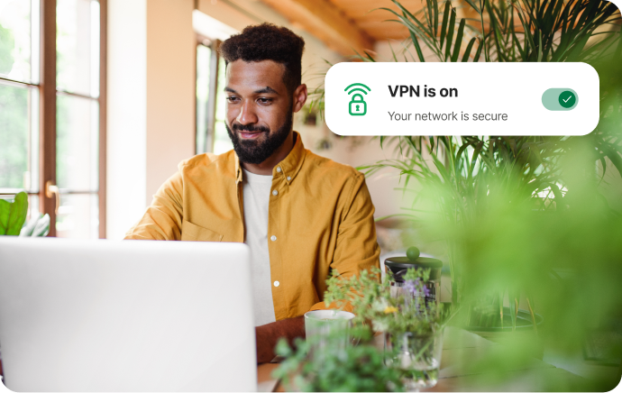 Homme entouré de plantes souriant à un ordinateur portable